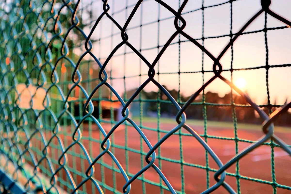 Fence line at sunset near a recreation field