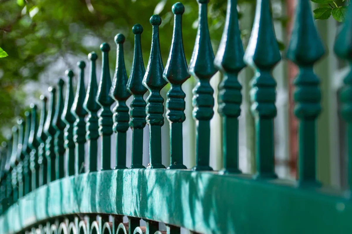 Ornamental iron fence finials in dappled light